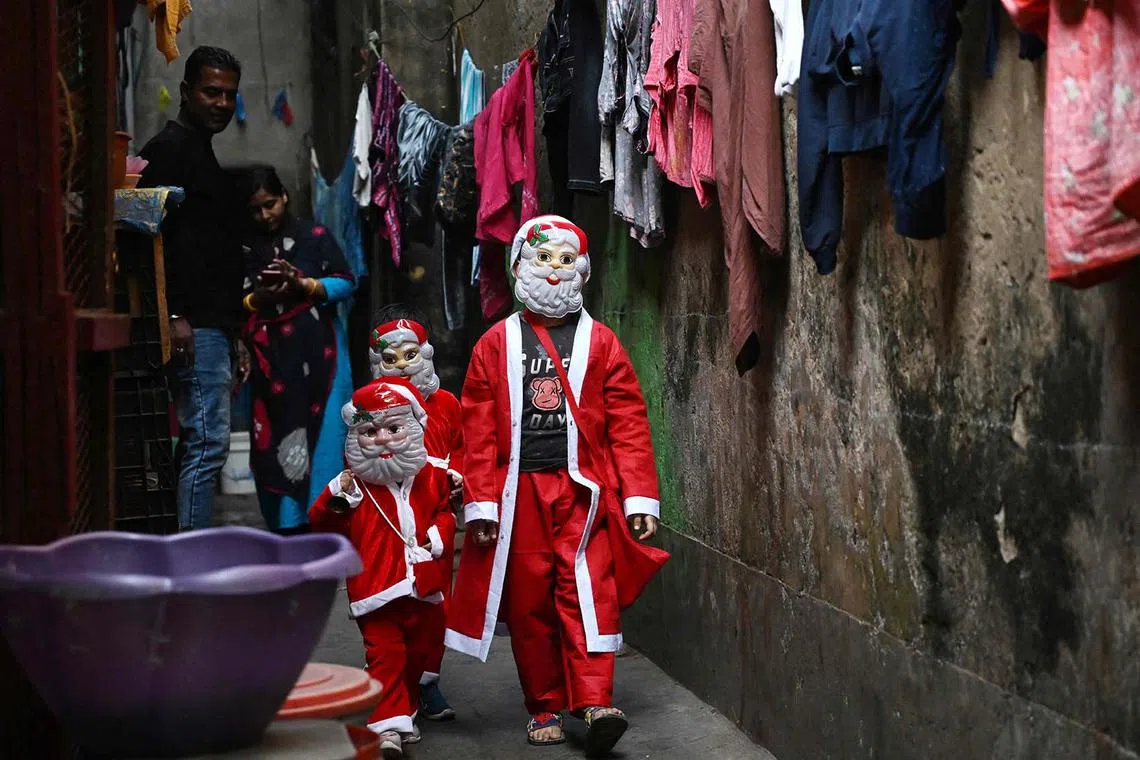 In this photograph taken on December 19, 2023, children dressed as Santa Claus walk along a street, ahead of Christmas festivities in Kolkata. (Photo by Dibyangshu SARKAR / AFP)