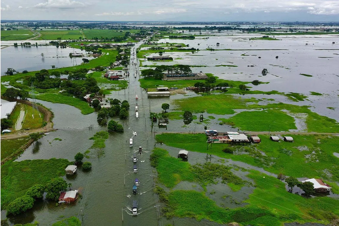 In this aerial view vehicles drive along the flooded Jujan Babahoyo road following heavy rains in Jujan, Guayas province, Ecuador, on March 12, 2025. (Photo by Marcos PIN / AFP)