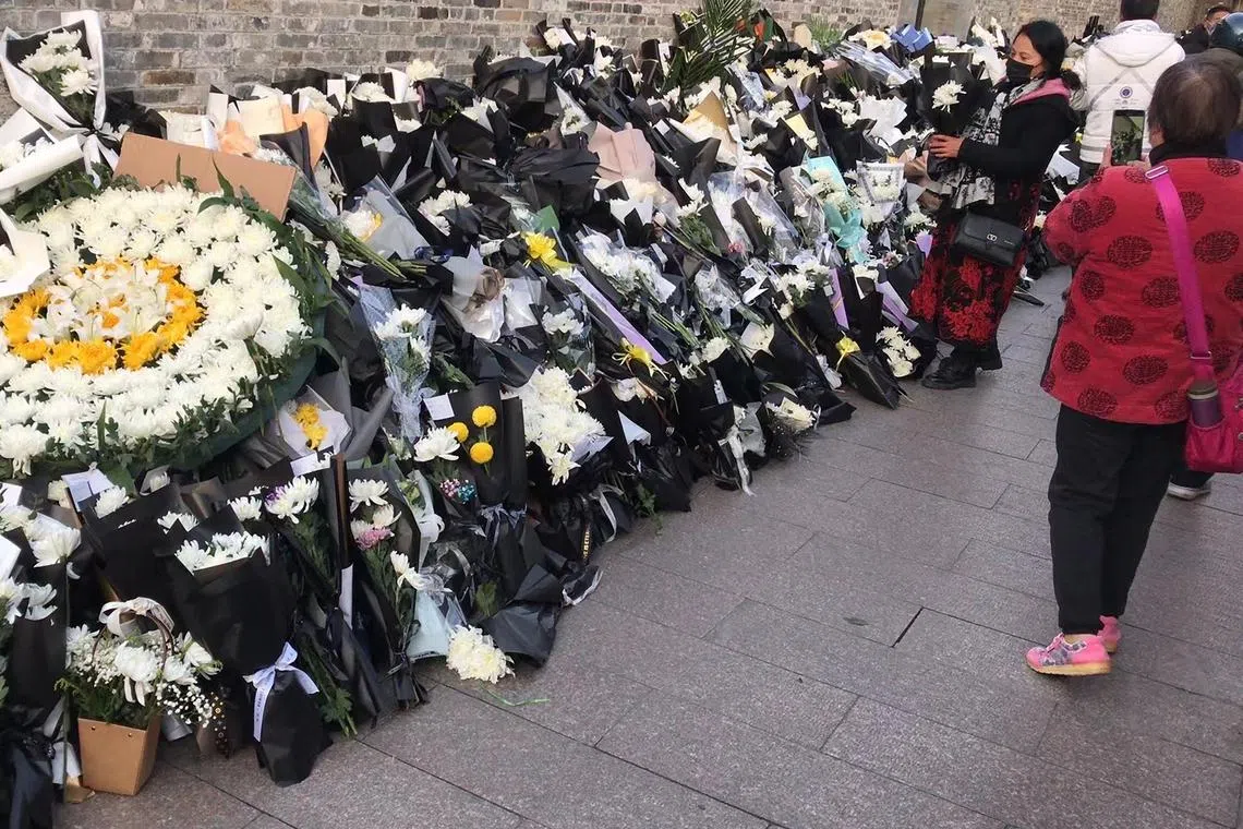 A mourner (second from right) places a flower bouquet with others placed outside the old home of former Chinese leader Jiang Zemin, who passed away on Nov 30, in Yangzhou, China, on Dec 1, 2022. 