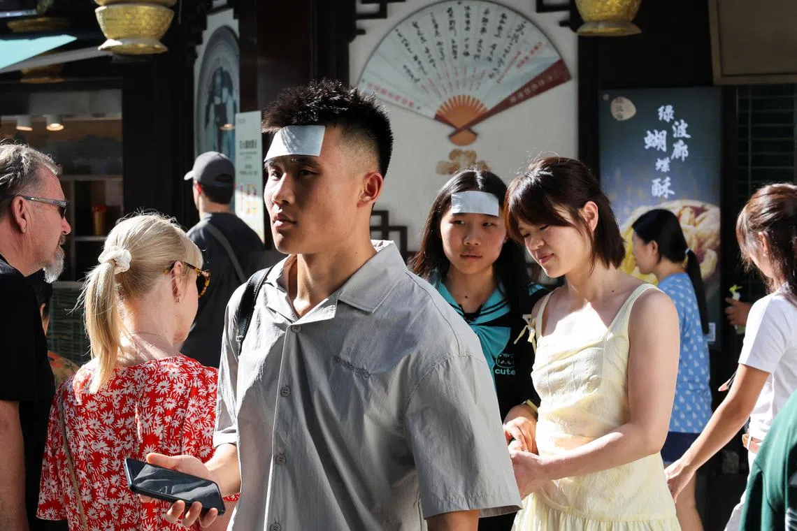 FILE PHOTO: People put cooling gel sheets on their foreheads to cool themselves amid a yellow alert for heat, in Shanghai, China July 4, 2025. REUTERS/Go Nakamura/File Photo