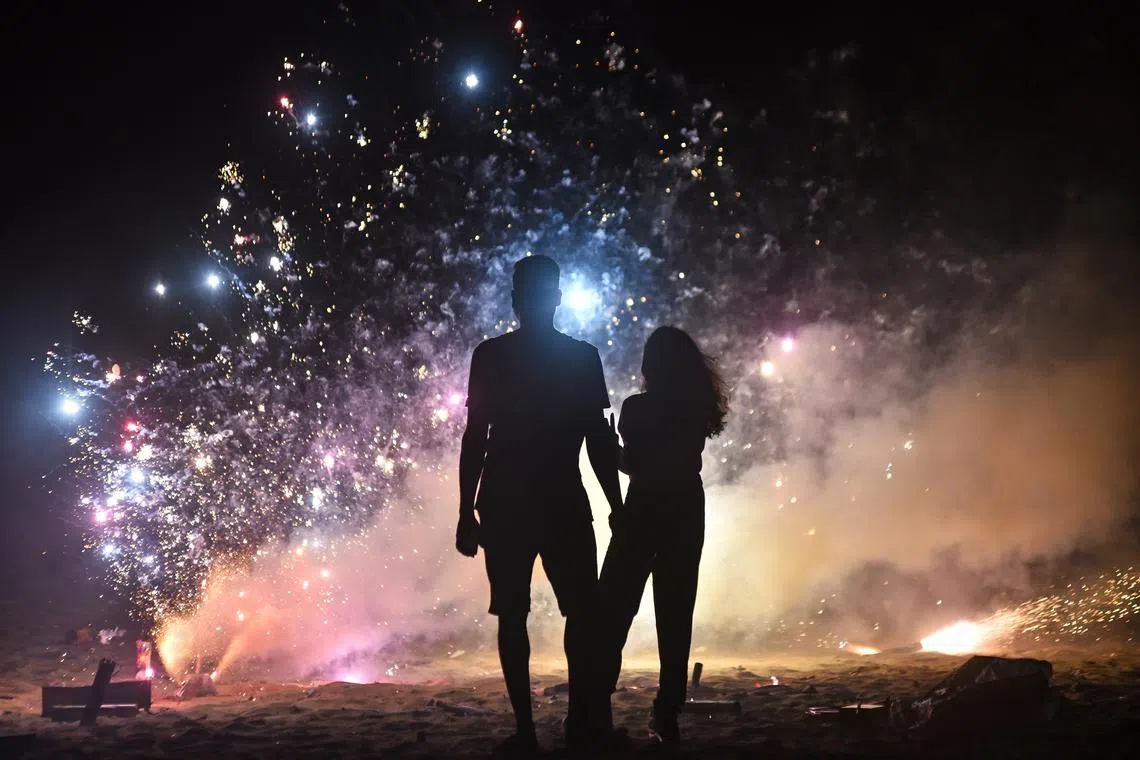 A couple lighting a firecracker on Diwali, the Hindu festival of lights, in Chennai, India on Nov 12, 2023. 