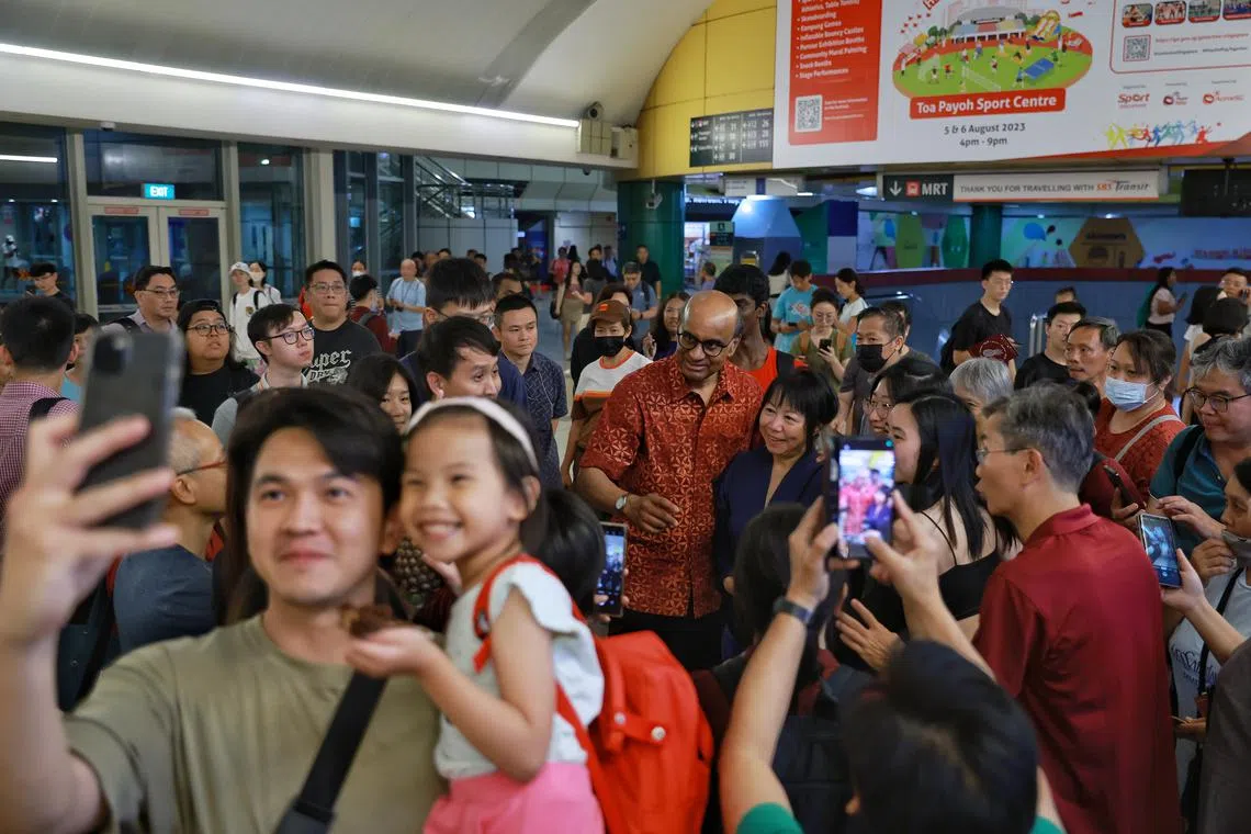 Members of the public taking photos with Presidential candidate Tharman Shanmugaratnam and his wife Jane Ittogi during a walkabout at Toa Payoh bus interchange on Aug 23, 2023.