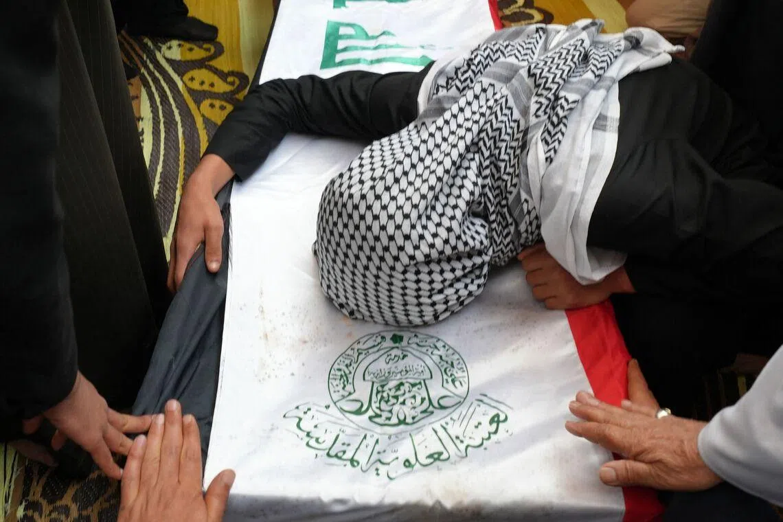 A family member mourning over the coffin of Ahmed Al-Jubouri, a member of Iraq's Ministry of Defense who was killed at the Habbaniyah military base following an aerial attack, during his funeral at the Imam Ali Shrine in the southern city of Najaf, Iraq on March 26, 2026.