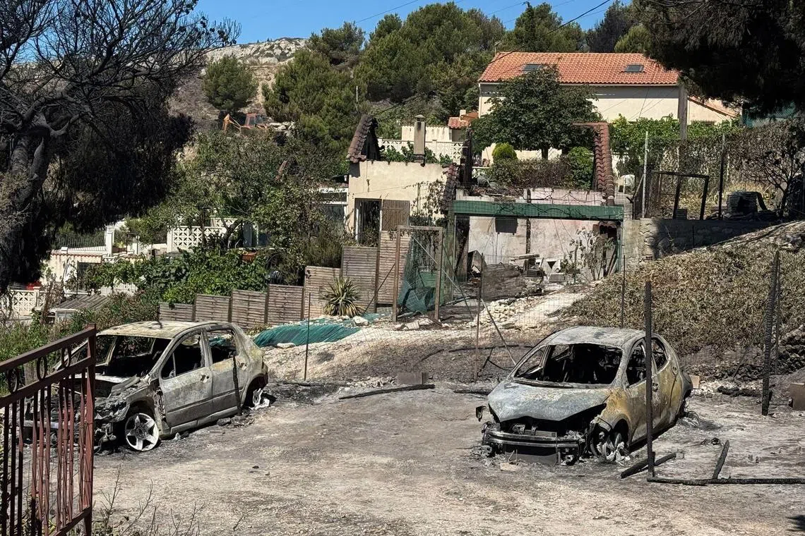 This general view shows burnt-out vehicles in Campagne Bleue of the L'Estaque District of Marseille, southern France on July 9, 2025, after a wildfire swept through areas close to the centre of the Meditteranean port city. A wildfire that disrupted plane and train in Marseille, France's second largest city has decreased in intensity, officials said. Several fires have raged in recent days in the southern region, fanned by winds and kindled by parched vegetation, including Tuesday's just north of the port city of Marseille. (Photo by Viken KANTARCI / AFP)