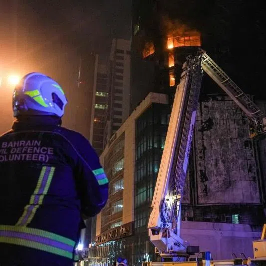 Emergency personnel work to extinguish a fire in a building after an Iranian strike in the Bahraini capital Manama on Feb 28, 2026.