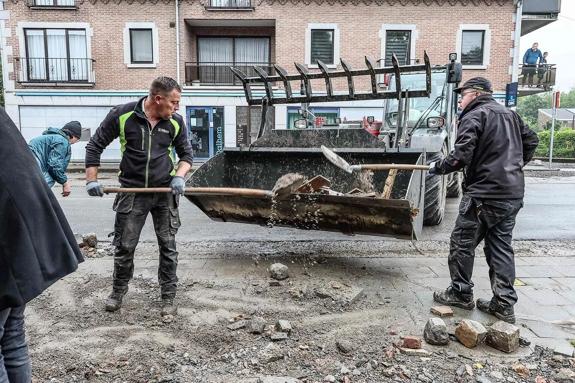 Residents clean up a flooded street the day after an episode of heavy rain in Dalhem, Belgium on May 18, 2024. 