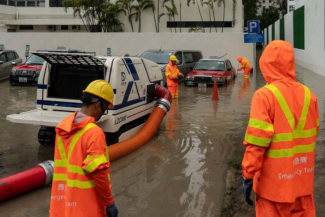 Emergency service workers from Hong Kong's drainage service department working to clear water from a flooded outdoor carpark in Tseung Kwan O on Aug 5, 2025. Parts of Hong Kong were brought to a standstill by flooding caused by heavy rains on Aug 5, after the highest-tier rainstorm warning was issued for the fourth time in eight days. 