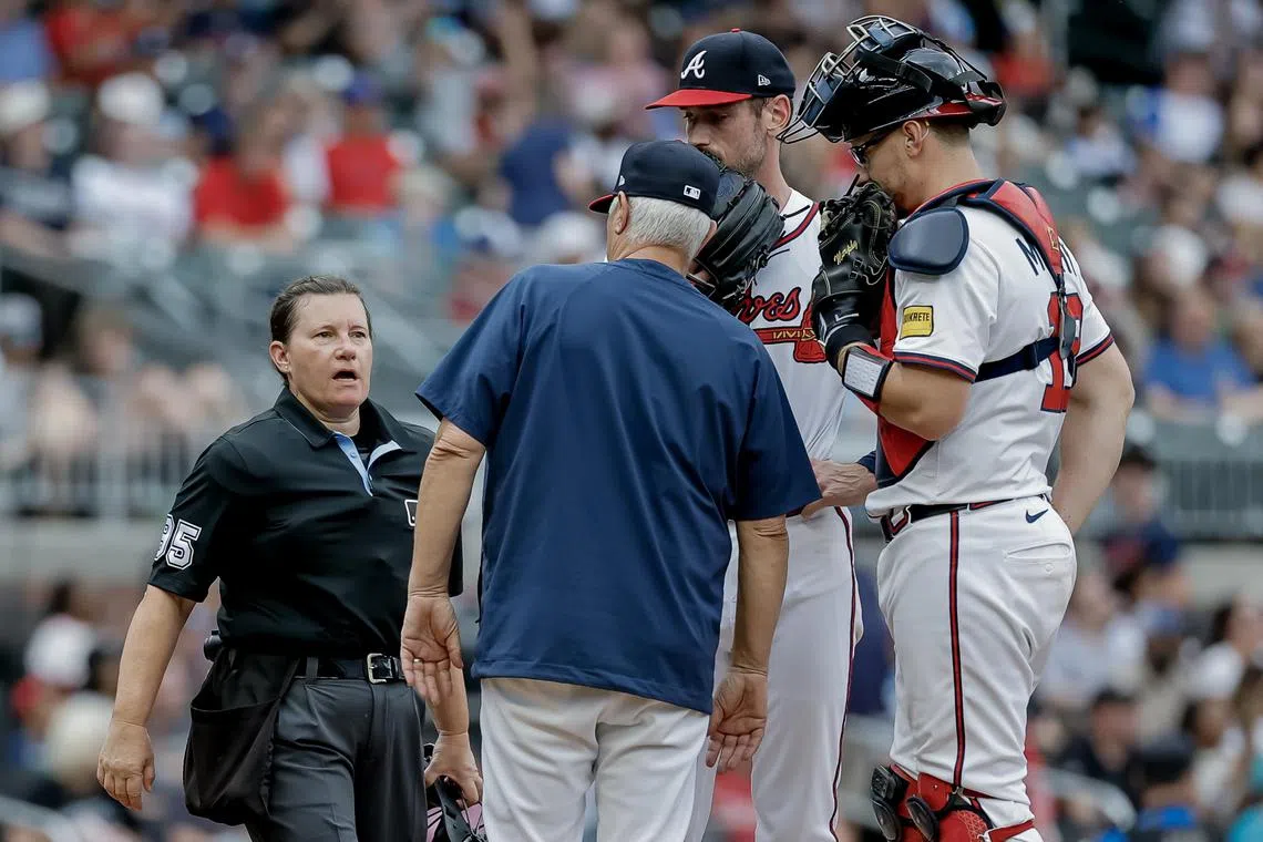 MLB home plate umpire Jen Pawol (in black) speaking with Atlanta Braves pitching coach Rick Kranitz (second from left) during a pitching mound visit in the second inning of an MLB baseball game between the Miami Marlins and the Atlanta Braves in Atlanta, Georgia on Aug 10.
