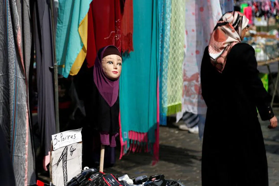 FILE PHOTO: A woman walks past a mannequin wearing an hijab headscarf at a market in the Brussels district of Molenbeek, Belgium, August 14, 2016.  REUTERS/Francois Lenoir/File Photo