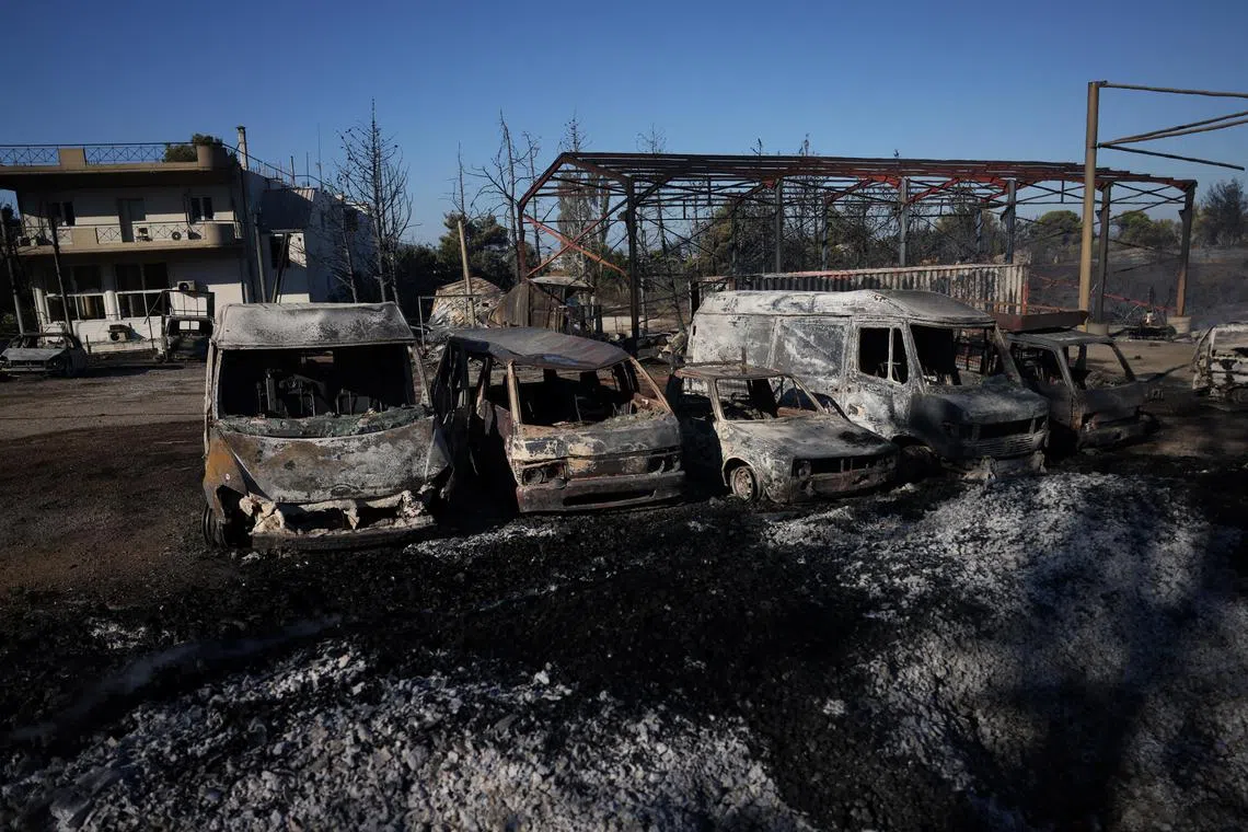 Burned cars are pictured outside a damaged factory following a wildfire in the Penteli area near Athens.