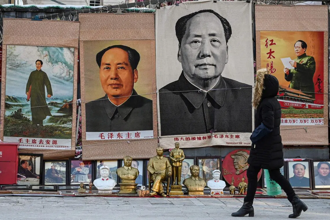 TOPSHOT - A woman walks past images depicting the late Chinese Communist leader Mao Zedong at a stall in an antique market in Beijing on December 26, 2023, the 130th birth anniversary of communist China's founding father. (Photo by Jade GAO / AFP)