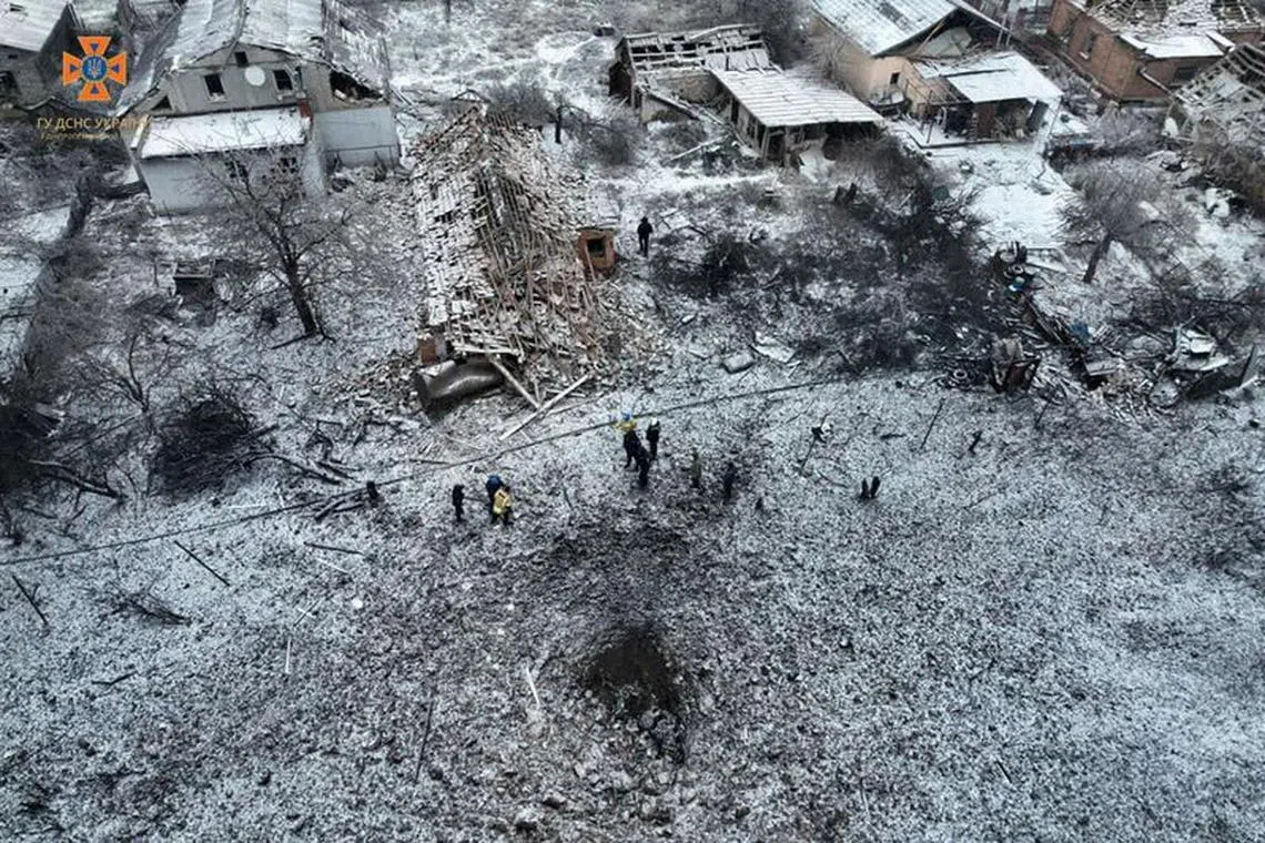 FILE PHOTO: People stand next to a destroyed residential house and a crater at the site of a Russian missile strike, amid Russia's attack on Ukraine, in Dnipropetrovsk Region, Ukraine January 8, 2024. Press service of the State Emergency Service of Ukraine in Dnipropetrovsk region/Handout via REUTERS/File Photo