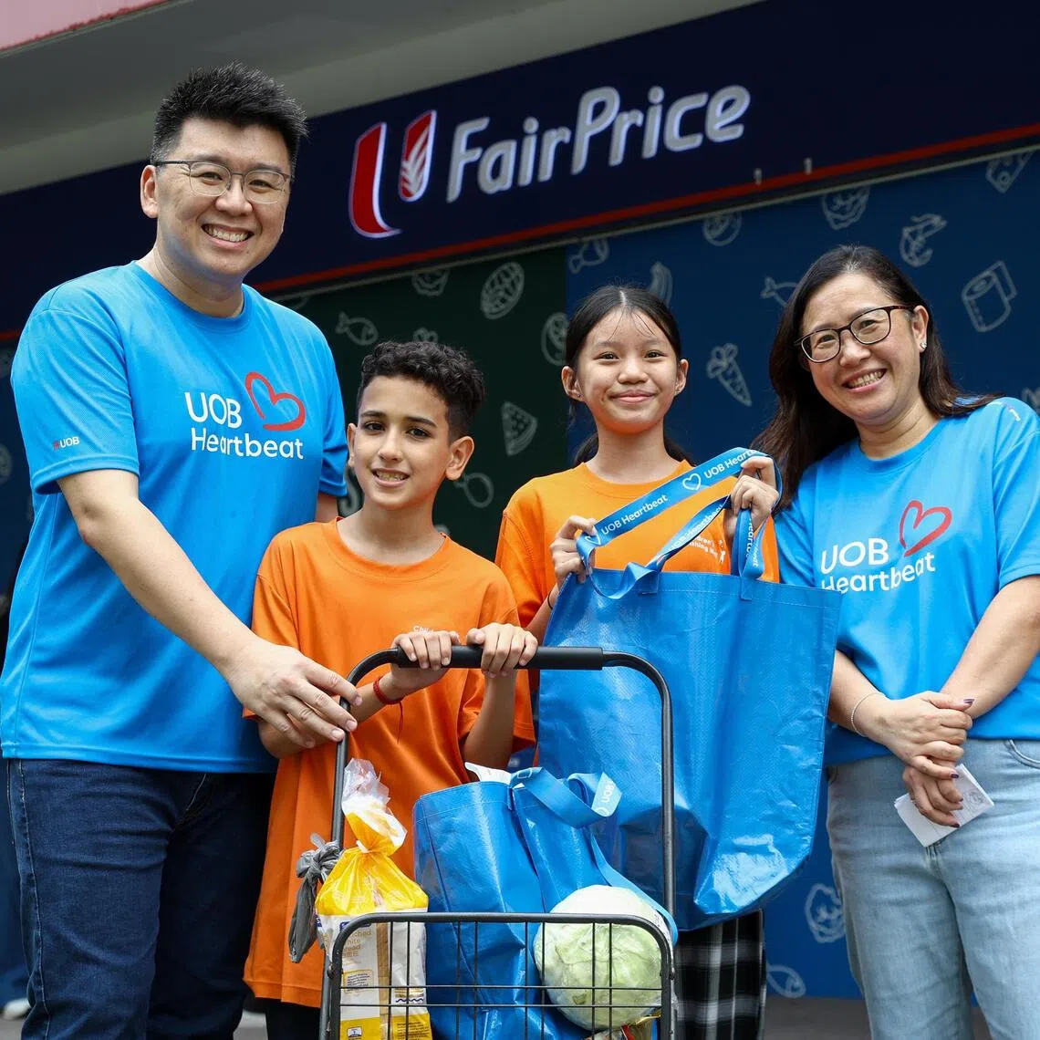 UOB Heartbeat volunteers Derrick Sin (left) and Jane Lai (right) with Aaron Kishen Arun Pandian Pillai, 11, and Najwa Chua Ai Xin, 12.