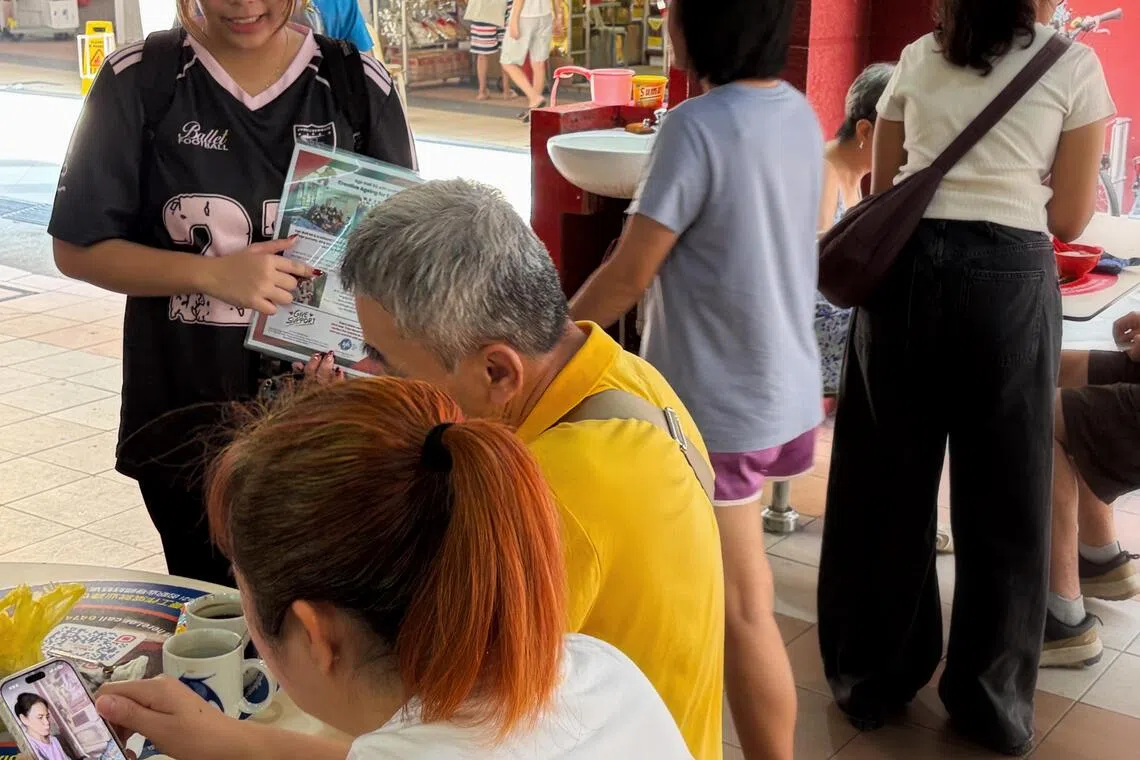 A woman seeking donations from members of the public at Kim Keat Palm Market & Food Centre in Toa Payoh.