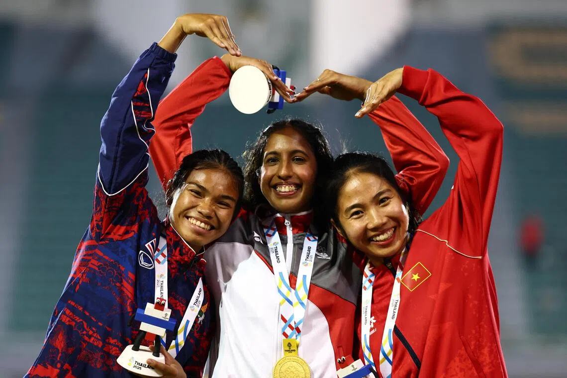 Gold medallist Singapore's Shanti Pereira celebrates on the podium during the women's 100m final medal ceremony with silver medallist Thailand's Jirapat Khanonta and bronze medallist Vietnam's Ha Thi Thu.