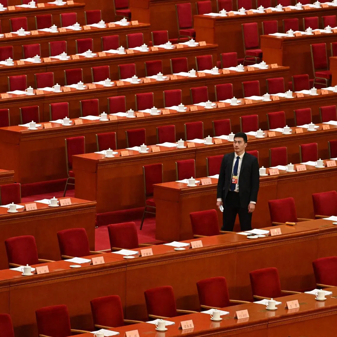 A security official walks past seats before the arrival of delegates for the opening ceremony of the Chinese People's Political Consultative Conference (CPPCC) at the Great Hall of the People in Beijing on March 4, 2024. (Photo by GREG BAKER / AFP)