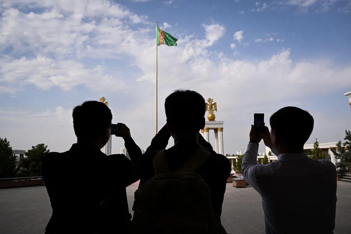 (FILES) The main flag of Turkmenistan sits in front of the State museum of the State cultural centre of Turkmenistan in the capital of Ashgabat on June 28, 2023. Three men who escaped one of the world's most secretive and repressive states have told AFP how they were tortured, beaten and subject to punishment rapes in penal colonies and psychiatric hospitals in Turkmenistan for the "crime" of being gay. When the oil- and gas-rich Central Asian republic makes the headlines, it is usually for the eccentricities of its "National Leader" and "Hero Protector" Gurbanguly Berdymukhamedov. But behind the monumental statues and the marble city of Arkadag built in Berdymukhamedov's honour, opponents and minorities are mercilessly persecuted, say Amnesty and Human Rights Watch, none more so than LGBT+ people. (Photo by Natalia KOLESNIKOVA / AFP)