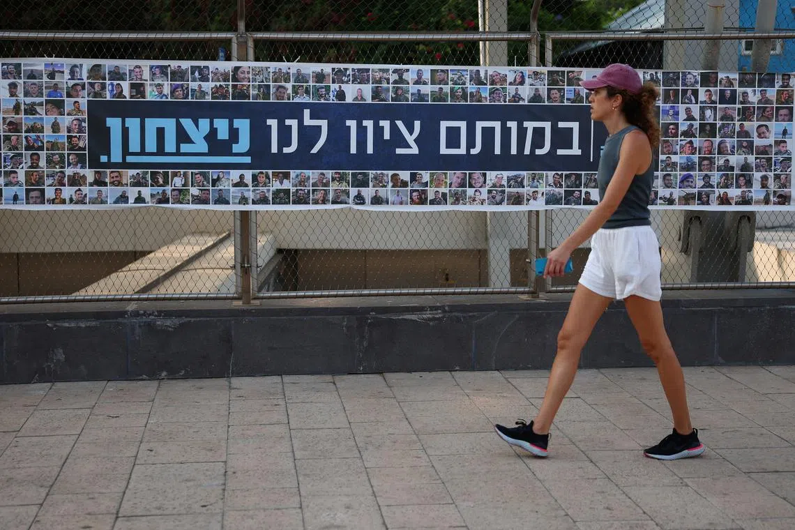 A woman walks past a banner depicting the faces of Israel’s fallen soldiers, amid the ongoing conflict in Gaza between Israel and Hamas, in Tel Aviv, Israel, August 19, 2024. REUTERS/Florion Goga/ File Photo