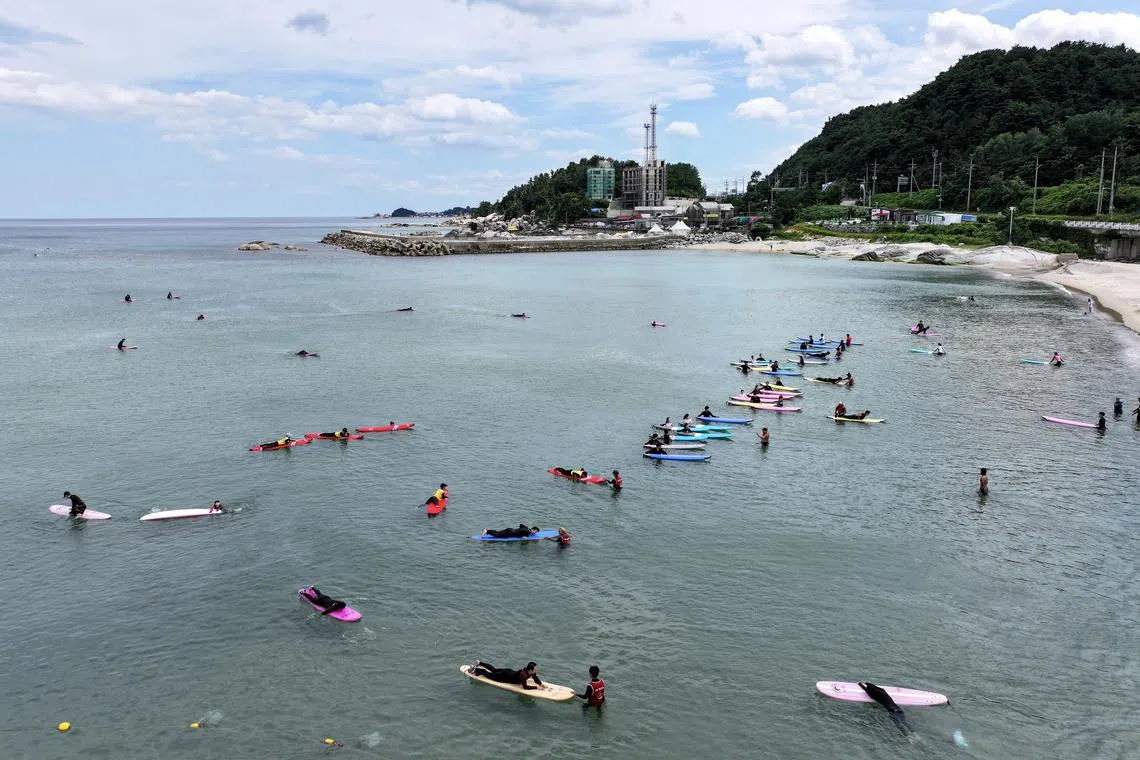 People surf amid a heat wave, in the sea off the coast of Yangyang, northeastern South Korea, on July 29.