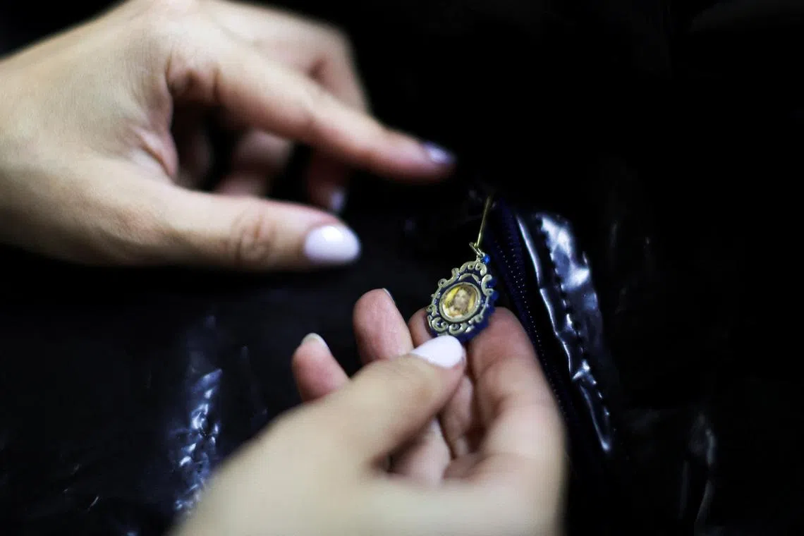 A worker attaches a depiction of Jesus Christ to a body bag before it is donated to rescue teams.