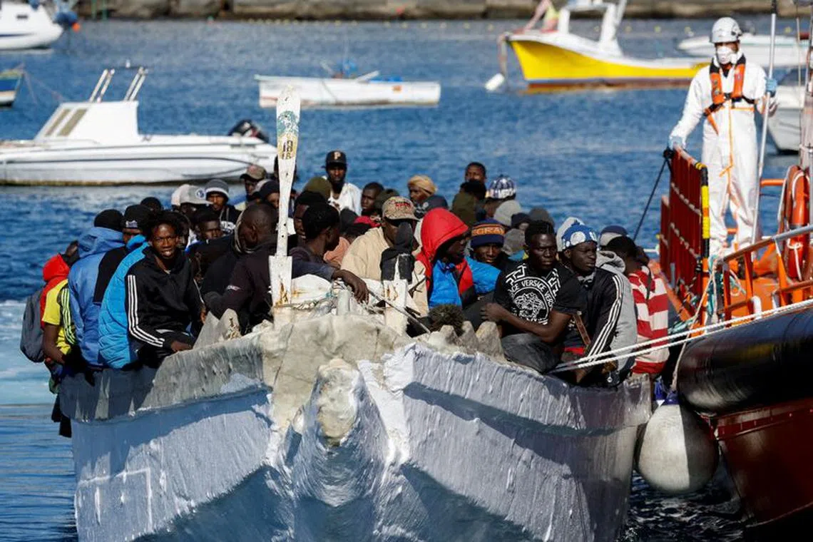 FILE PHOTO: A group of migrants wait to disembark from a wooden boat after being rescued by a Spanish coast guard vessel in the port of Arguineguin, on the island of Gran Canaria, Spain, January 2, 2024. REUTERS/Borja Suarez/File Photo