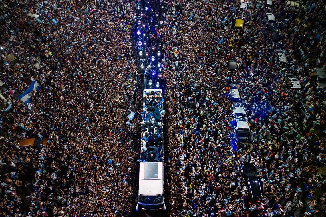 TOPSHOT - Argentina's players celebrate on board a bus with supporters after winning the Qatar 2022 World Cup tournament as they leave Ezeiza International Airport en route to the Argentine Football Association (AFA) training centre in Ezeiza, Buenos Aires province, Argentina on December 20, 2022. (Photo by Tomas CUESTA / AFP)