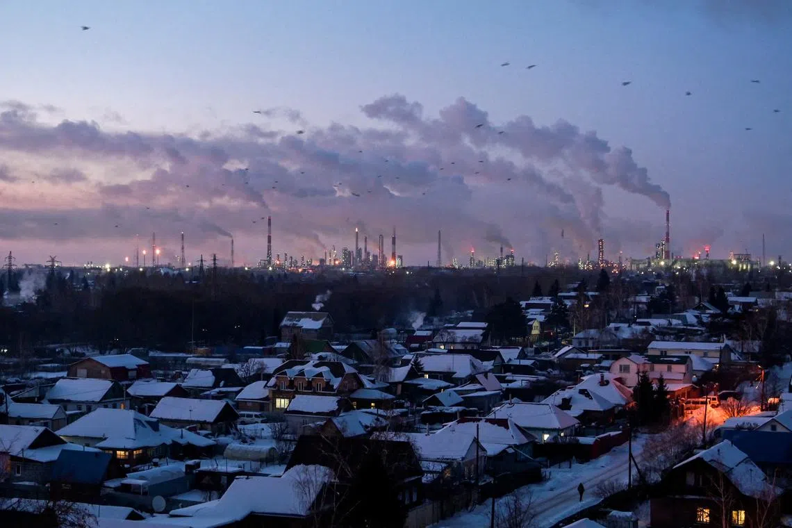 FILE PHOTO: Birds fly above buildings as flue gas and steam rise out of chimneys and smokestacks of an oil refinery during sunset on a frosty day in the Siberian city of Omsk, Russia, February 8, 2023. REUTERS/Alexey Malgavko/File Photo