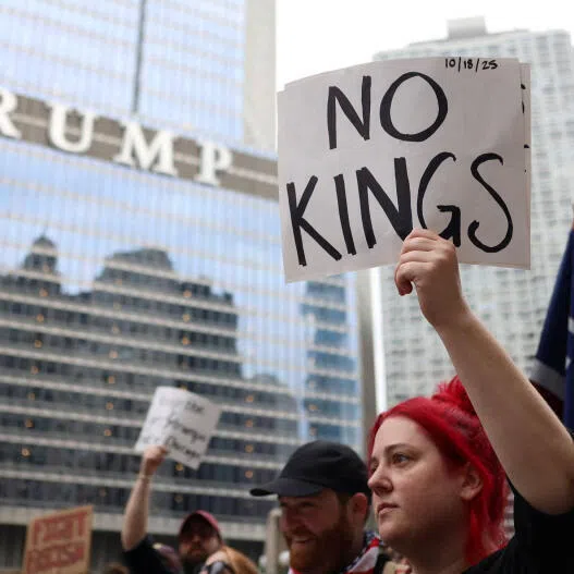 A demonstrator holds a sign in front of Trump International Hotel and Tower, as people gather for a "No Kings" protest in Chicago, Illinois, USA.