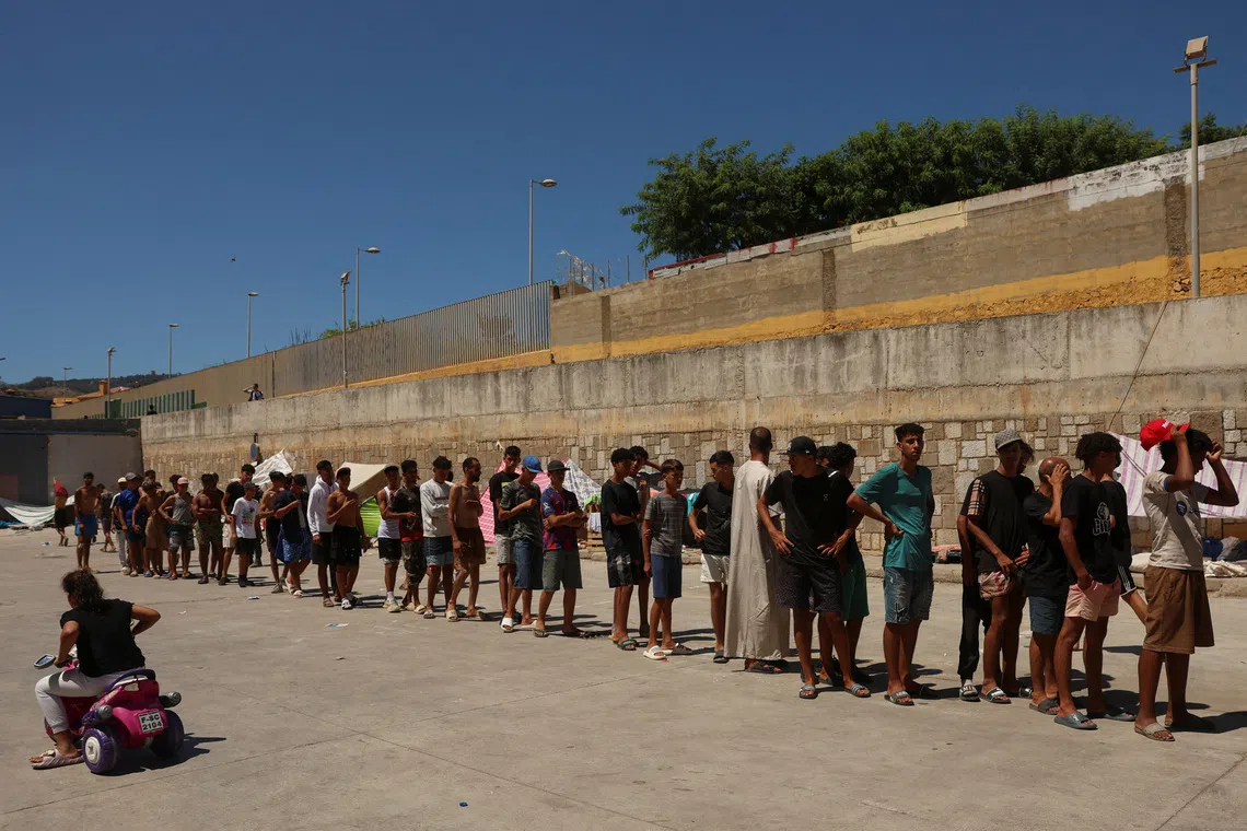 Migrants, some of them minors, queue to receive food staples from local NGO Media Luna Blanca on Aug 6.