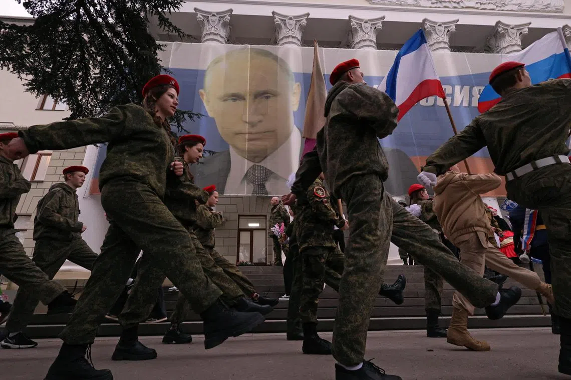 Participants march in front of a banner featuring a portrait of Russian President Vladimir Putin, during an event in Crimea marking   the ninth anniversary of Russia's annexation of the Ukrainian peninsula.