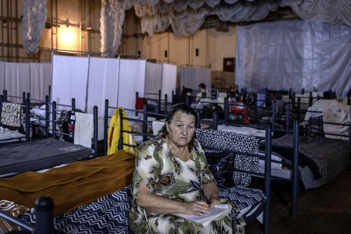 Valentina Shevchenko, a children’s author who evacuated with others, writes at a shelter in Pavlograd, Ukraine, on Aug 15. 