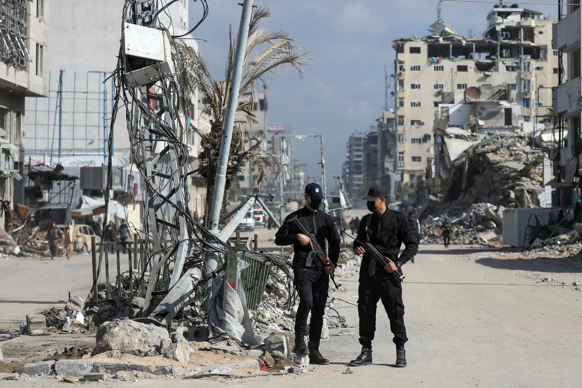 Hamas policemen stand guard near the rubble after deploying in streets to maintain order, following a ceasefire between Israel and Hamas, in Gaza City.