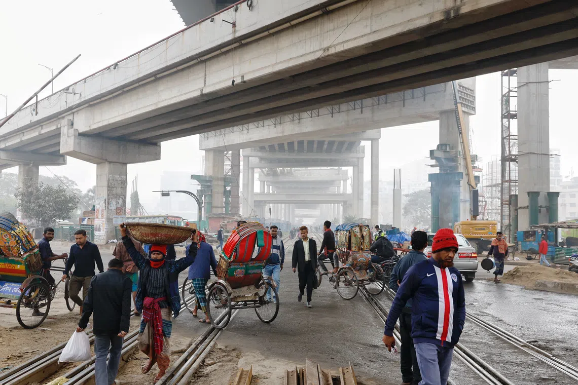 People and vehicles pass through rail tracks at the Karwan Bazar area, in Dhaka, Bangladesh, January 23, 2025. REUTERS/Mohammad Ponir Hossain