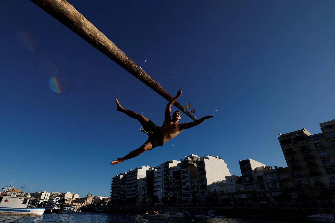 A competitor falls off the "gostra", a wooden pole covered in lard, during the celebrations for the religious feast of St Julian, patron of the town of St Julian's, Malta, August 31, 2025. REUTERS/Darrin Zammit Lupi TPX IMAGES OF THE DAY