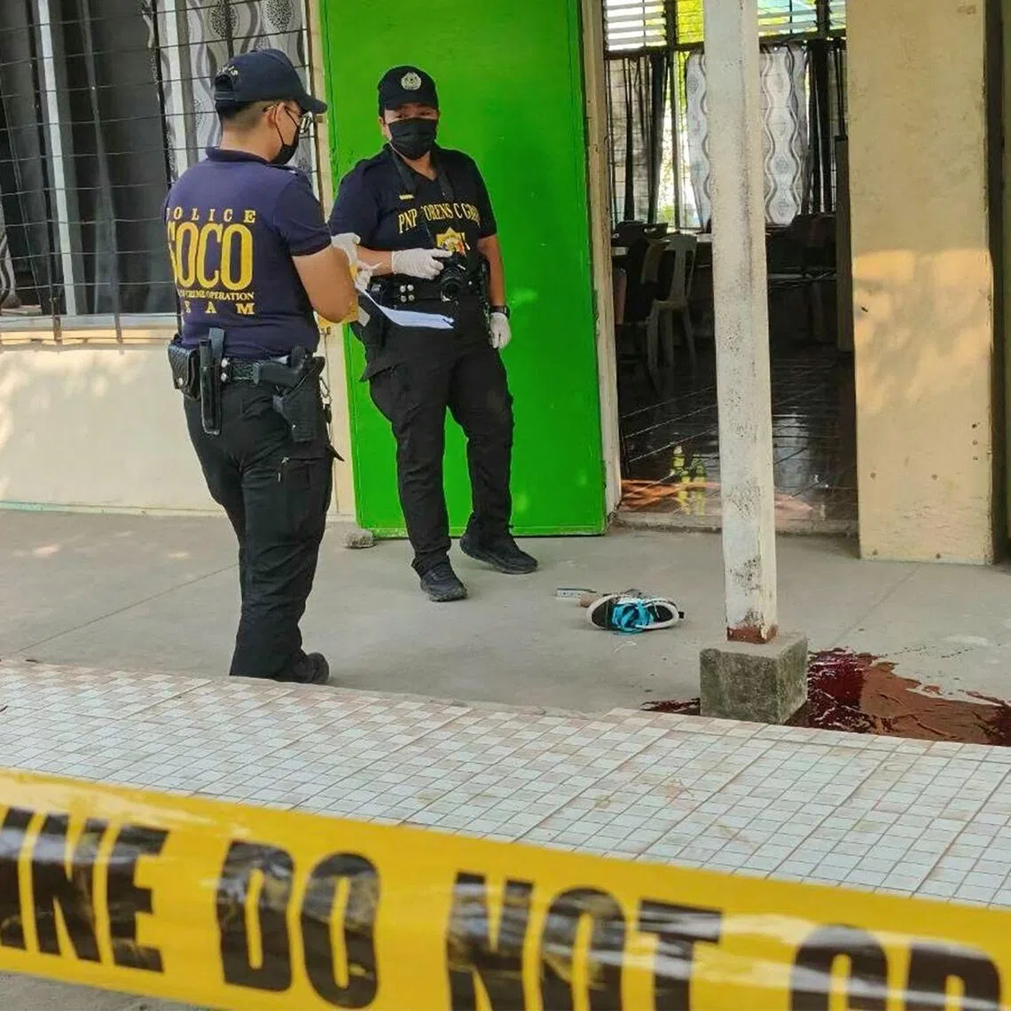Police investigators stand next to a pool of blood after a shooting incident at a classroom entrance in a high school in Banga town, South Cotabato, in southern island of Mindanao on September 18, 2026. A student killed at least two people at a school in the southern Philippines on Friday before turning the gun on himself, officials told AFP, the country's third deadly campus attack since June. (Photo by AFP)