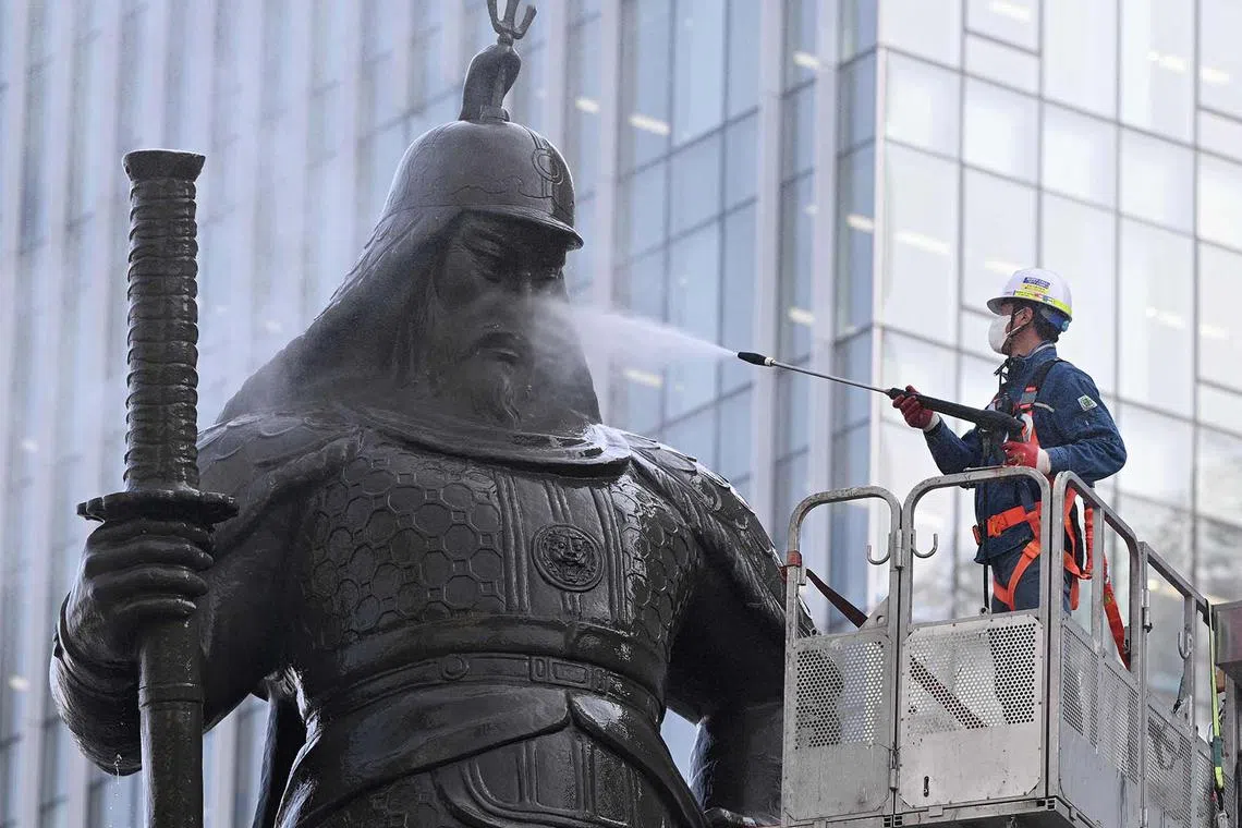 TOPSHOT - A worker sprays water to wash the bronze statue of Admiral Yi Sun-shin, who won a major naval victory over Japan in the 16th century, during a street and park clean-up event for spring at Gwanghwamun square in Seoul on April 16, 2025. (Photo by Jung Yeon-je / AFP)