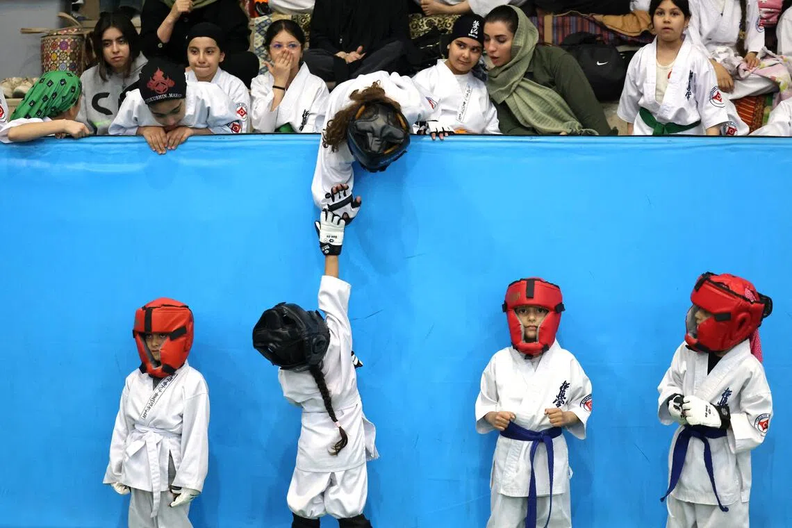 A young athlete reaches up to give a "high-five" during the women's karate competition, made-up of clubs and teams from around the Tehran province.