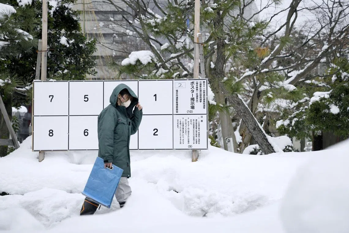 A person walks past a bulletin board for posters of candidates for the February 8 snap election, where snow has accumulated, in Fukui, Japan, January 26, 2026, in this photo taken by Kyodo. Mandatory credit Kyodo/via REUTERS