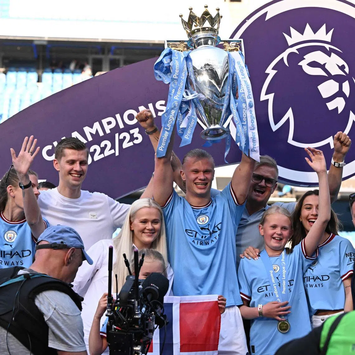 Manchester City's Erling Haaland lifting the Premier League trophy as he celebrates with his family after the presentation ceremony.