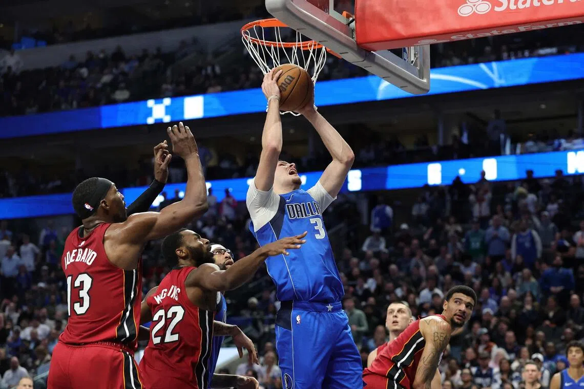 Cooper Flagg of the Dallas Mavericks is defended by Andrew Wiggins and Bam Adebayo of the Miami Heat during the second half at American Airlines Center.