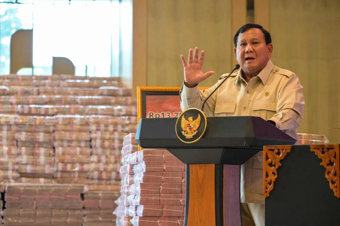 Indonesian President Prabowo Subianto speaks beside stacks of Indonesian rupiah banknotes equivalent to 800 million USD at the Attorney General's Office building during the handover of assets recovered from the corruption case involving the provision of Crude Palm Oil export facilities, in Jakarta on October 20, 2025. (Photo by BAY ISMOYO / AFP)