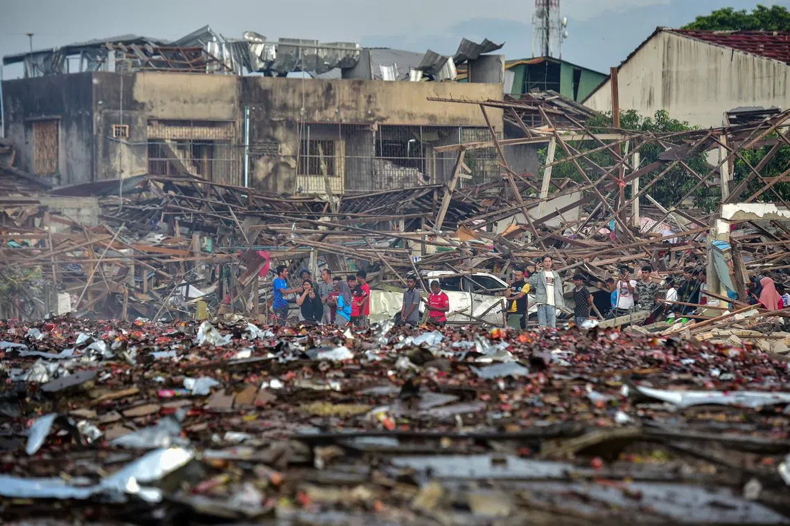 People looking at the aftermath of destroyed homes after an explosion ripped through a firework warehouse, killing at least 10  people and injuring more than 100, in Sungai Kolok district in the southern Thai province of Narathiwat on Saturday. 