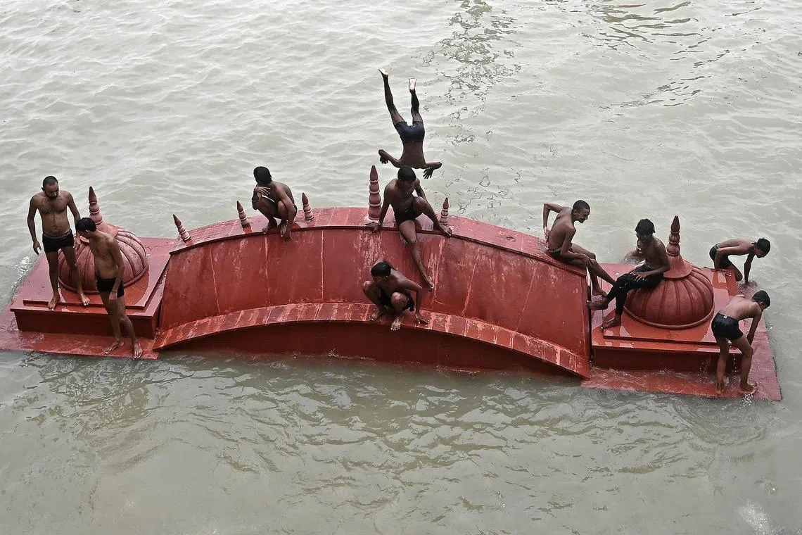 Youths standing on a submerged portion of a temple as they prepare to dive while playing in the flood waters of river Ganges after heavy monsoon rains in Prayagraj on September 15, 2024. 