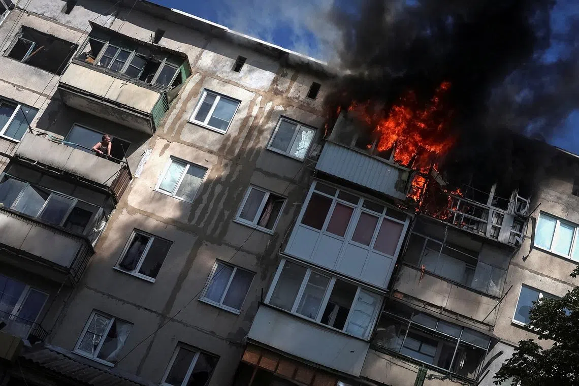 A resident watches from his balcony as another flat burns after being hit by a Russian drone, amid Russia's attack on Ukraine, in the frontline town of Druzhkivka, in Donetsk region, Ukraine, June 22, 2026. REUTERS/Anatolii Stepanov