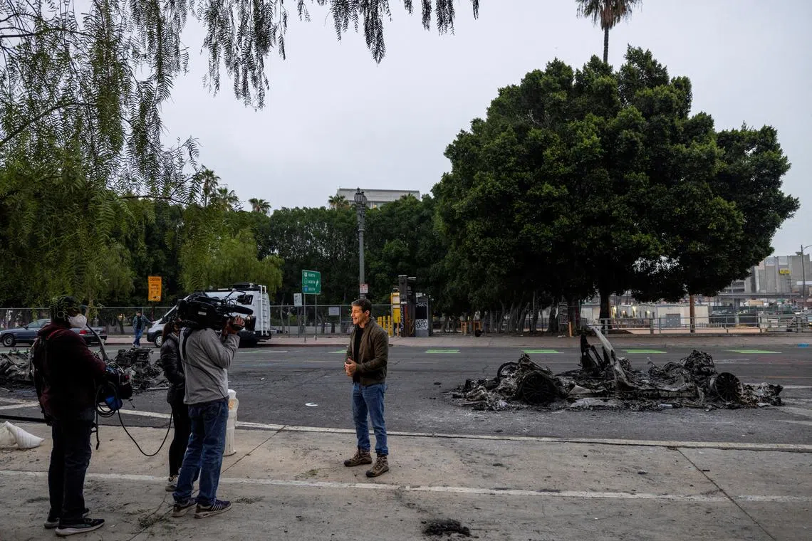 FILE PHOTO: Members of the media report from Los Angeles Street where Waymo cars were burned yesterday, after the California National Guard was deployed by U.S. President Donald Trump as a response to protests against federal immigration sweeps, in downtown Los Angeles, California, U.S., June 9, 2025.   REUTERS/Jill Connelly/File Photo