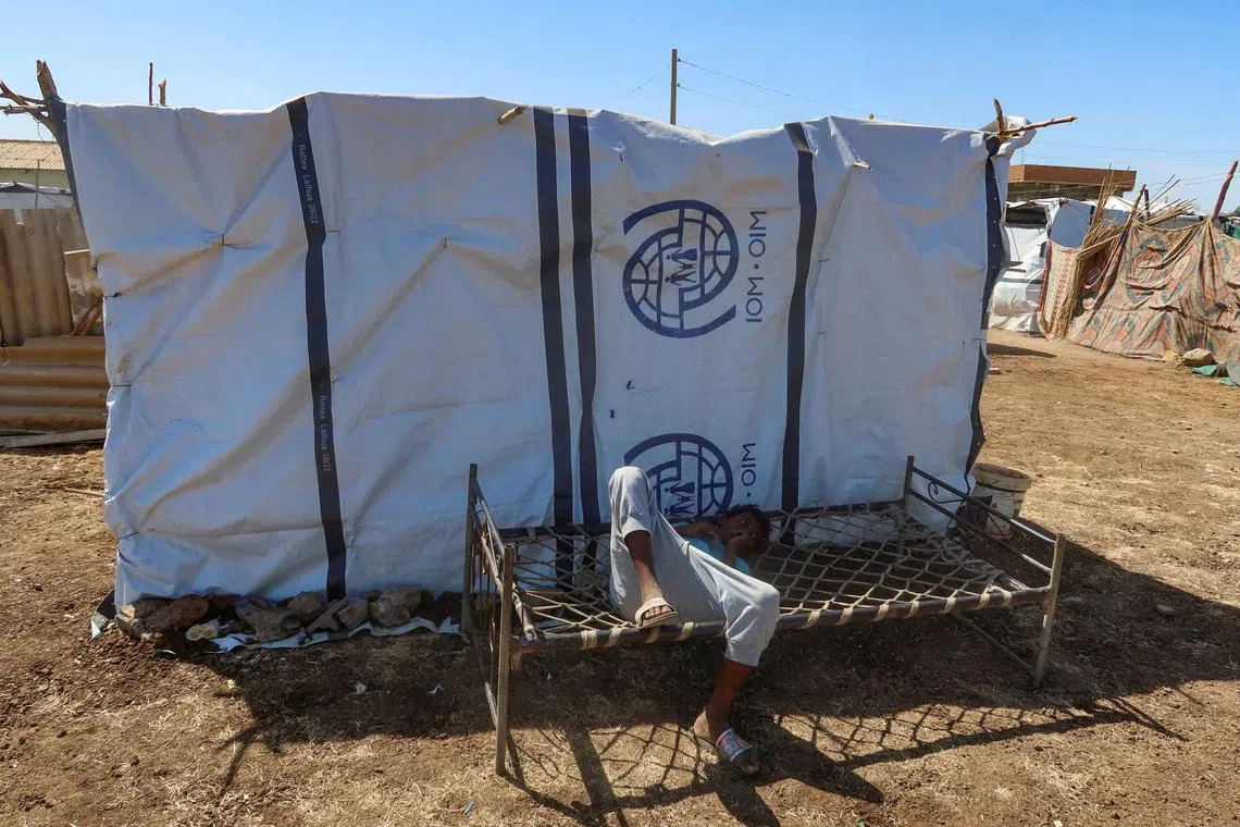 FILE PHOTO: A boy displaced from Sudan's Gezira state due to Rapid Support Forces violence, lies down on a bench with the logo of the International Organization for Migration in New Halfa, Sudan, November 2, 2024. REUTERS/El Tayeb Siddig/File Photo