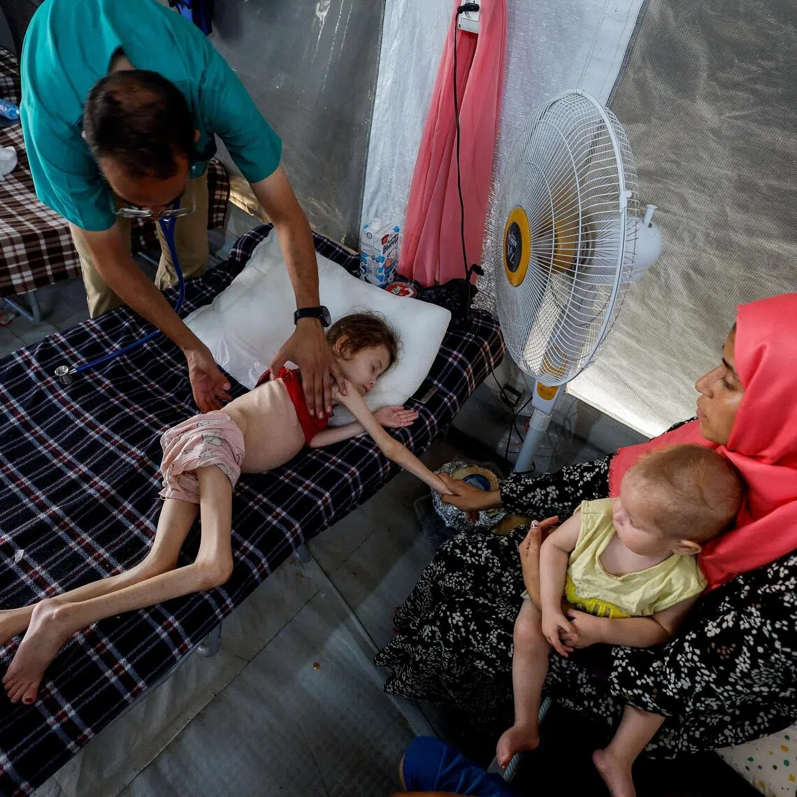A doctor checks Jana Ayad, a malnourished Palestinian girl, at a field hospital in southern Gaza.
