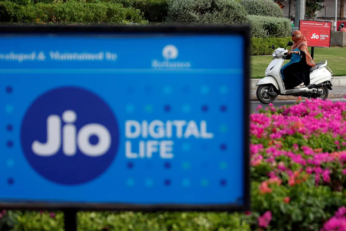 FILE PHOTO: A woman rides her scooter past advertisements of Reliance Industries' Jio telecoms unit, in Ahmedabad, India, July 5, 2018. REUTERS/Amit Dave/File Photo