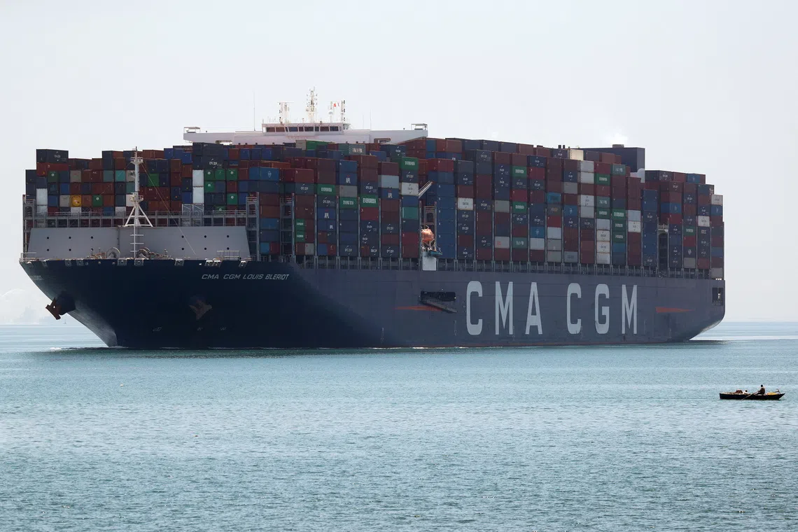 A fisherman travels on a boat in front of a CMA CGM container ship passing through the Suez Canal in Ismailia, Egypt July 7, 2021. Picture taken July 7, 2021. REUTERS/Amr Abdallah Dalsh