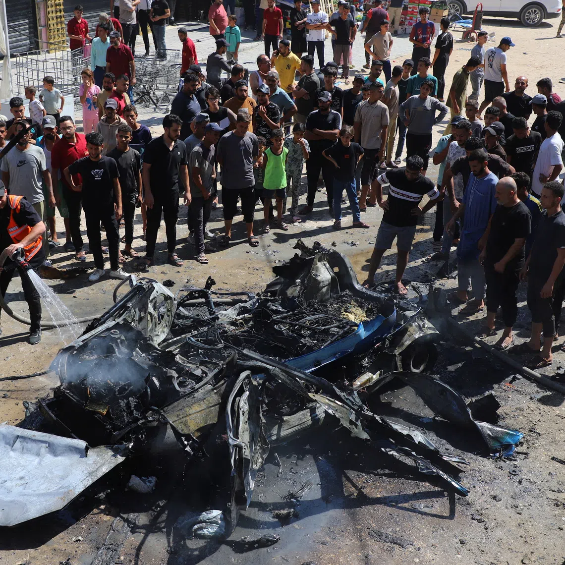 Residents gather as fire is extinguished following an Israeli airstrike that hit a vehicle in Gaza City, August 31, 2026. REUTERS/Ebrahim Hajjaj
